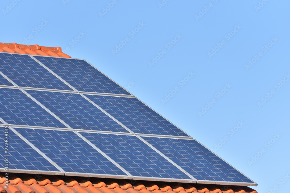 Solar panels installed on the roof of a house with tiles in Europe against the background of a blue sky. Green technology Solar panels installed on the roof of a house with tiles in Europe against the background of a blue sky. Green technology
