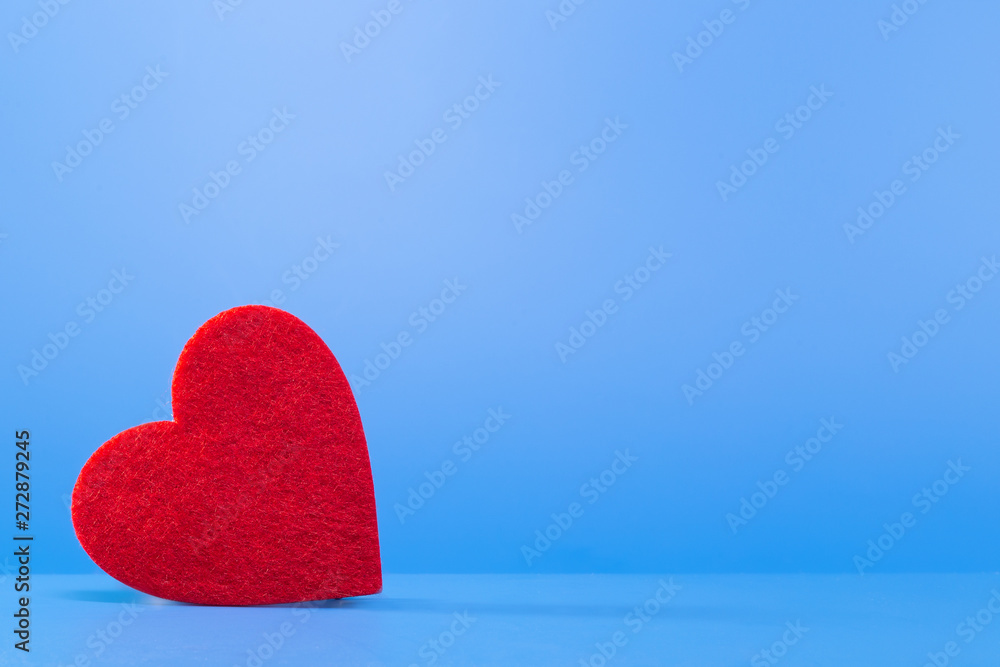 Fototapeta premium Bright red heart on a blue background in the left corner