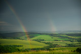 Summer landscape after storm, rainbow and green meadow