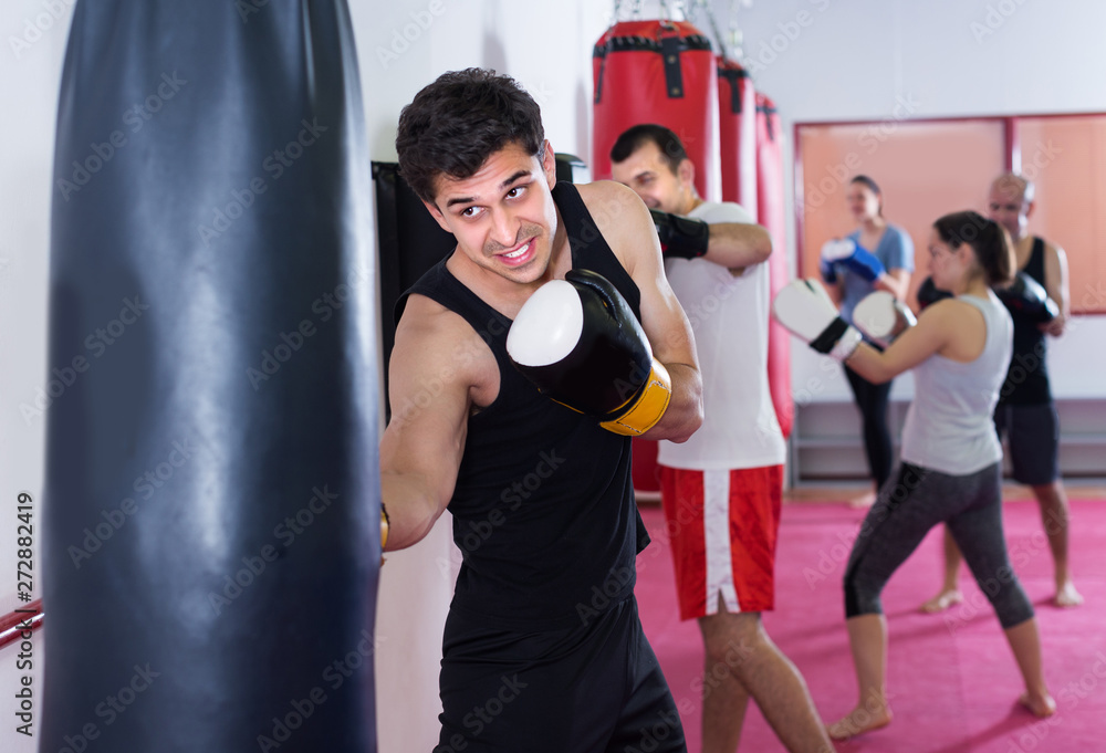 Young athlete male is beating a boxing bag