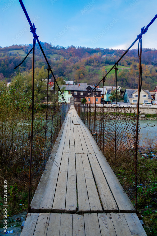 Obraz premium &nbsp; Power transformer for an urban area, lit by a bright sun, on a metal pole isolated against a blue sky