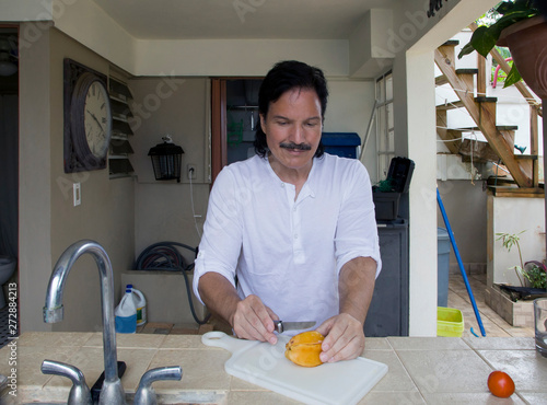 Hispanic man cutting star fruit with knife
