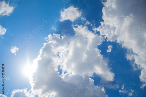 Blue sky background with clouds and sunlight.