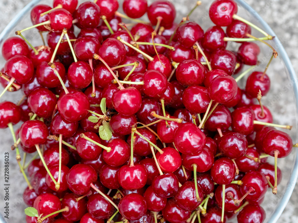 Ripe juicy red cherries in a transparent plate. A rich harvest of healthy berries. Natural vitamins. Photo view from the top. Ripe juicy red cherries in a transparent plate. A rich harvest of healthy berries. Natural vitamins. Photo view from the top.