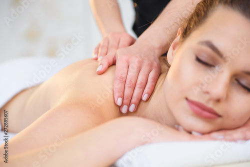 Handsome relaxing woman during massage in spa salon.