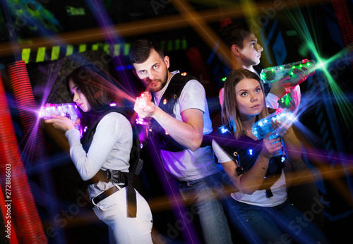 Young people in bright beams during laser tag game