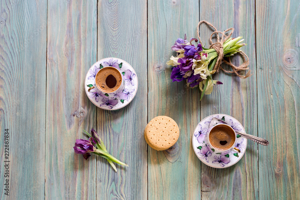 A cup with morning coffee and a bouquet of wildflowers