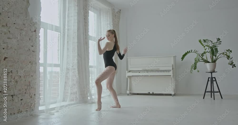 Beautiful slender barefoot woman in black bodysuit dancing sensually in light white room - slow motion Beautiful slender barefoot woman in black bodysuit dancing sensually in light white room - slow motion