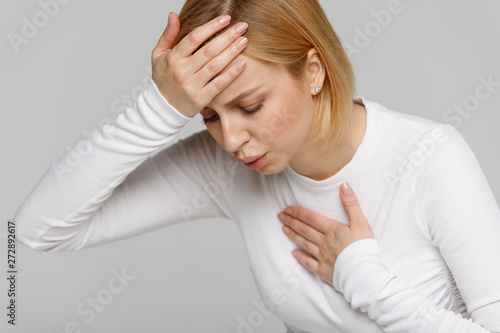 Breathing, respiratory problem, asthma attack, pressure, chest pain, sun stroke, dizziness concept. Studio portrait of woman received heatstroke in hot summer weather, touching her forehead, isolated