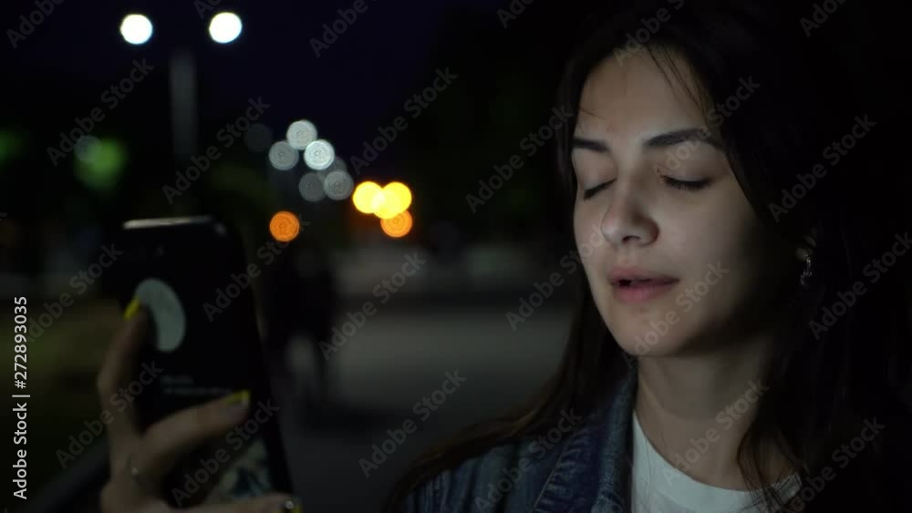 cheerful cute girl talking on the phone in video call on the street late night in the park cheerful cute girl talking on the phone in video call on the street late night in the park