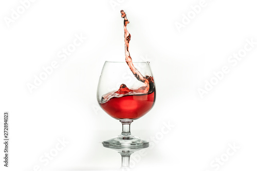 Red wine splashing out of a glass, isolated on white. Concept: alcoholic drinks