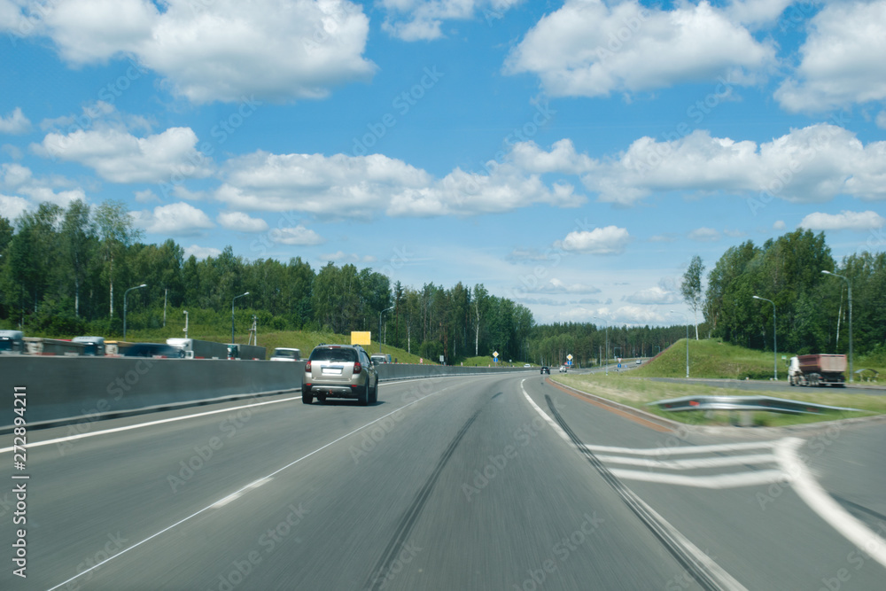 A trip by car to the beautiful places of the city of St. Petersburg. The sunny sky with a beautiful roadside landscape and moving along the path and on the counter road in a stream of cars.