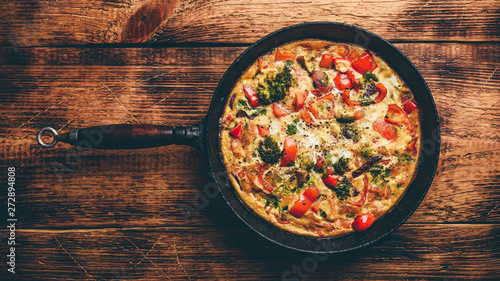 Vegetable frittata with broccoli, red bell pepper and red onion in cast iron skillet. View from above photo