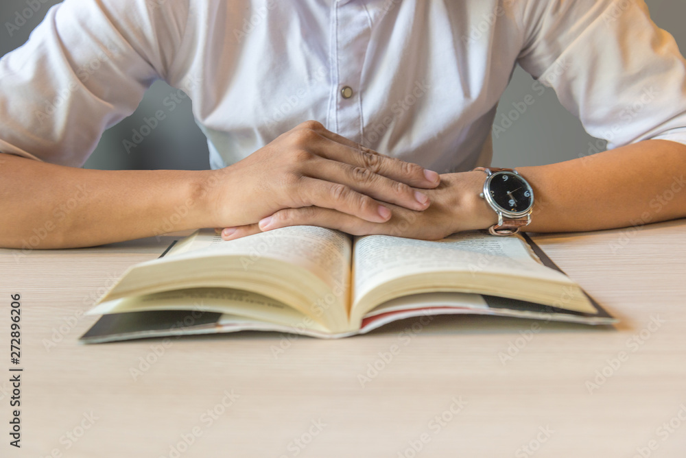 Close of man hands putting on book on table Close of man hands putting on book on table