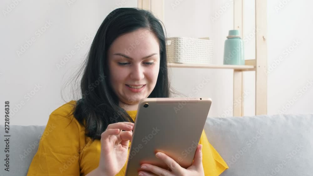 Portrait of a young beautiful woman in yellow t-shirt who uses a tablet. Portrait of a young beautiful woman in yellow t-shirt who uses a tablet.