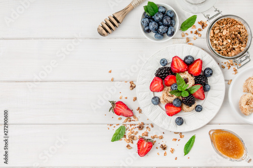 Healthy breakfast with granola, fruits, berries on white background.