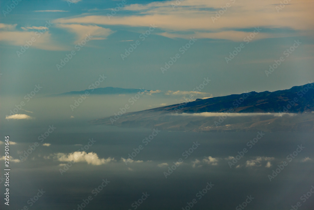 La Gomera and El Hierro islands, flying in the air between different clouds. Bright blue sky. View from 1900m of altitude. Teide National Park, Tenerife, Canary Islands.
