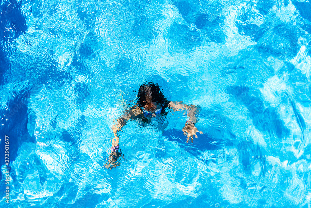 Girl dived and swimming in her private pool in the sun during her summer vacation.