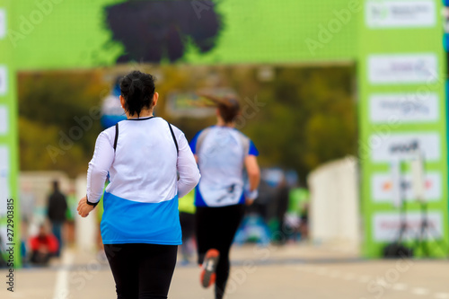 Two women seen from behind running a marathon are reaching the final line