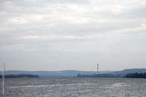 Belgrade under the rain seen from Zemun, with an industrial chimney in background in front, on the Danube river, and seagulls flying in front © Jerome