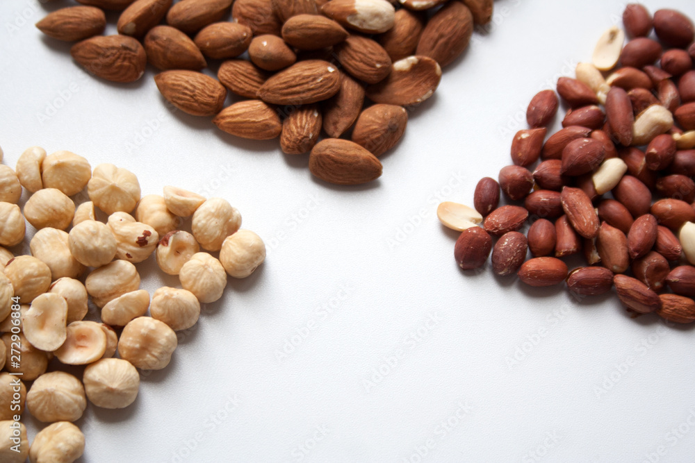 Fototapeta premium Hazelnuts, almonds and peanuts on white background closeup