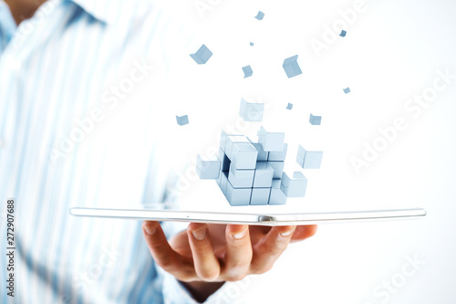 Businessman hand holding a tabalet with abstract cube puzzle. Mixed media photo