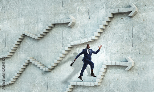 Black businessman climbing stone stairs illustrating career development and success concept. Mixed media