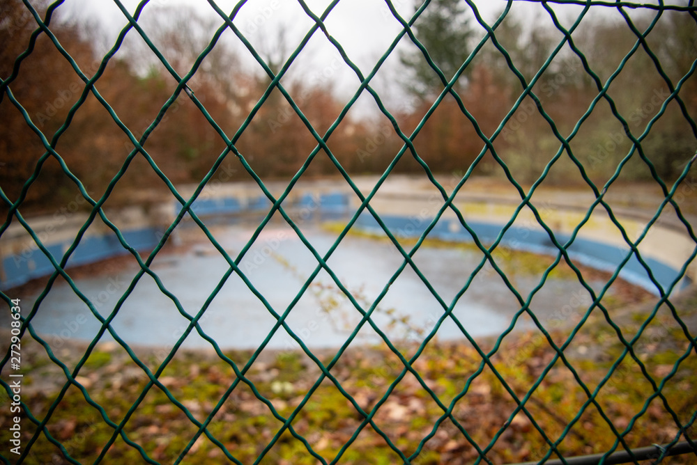 Clôture devant une piscine abandonnée Clôture devant une piscine abandonnée