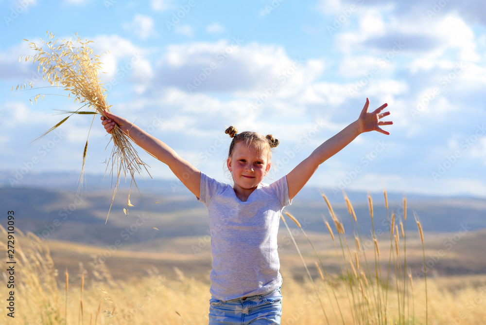 Young girl in a field celebrating Shavuot the summer harvest festival. Nature beauty, blue sky, white clouds and field of wheat.