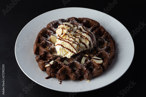 chocolate Belgian waffles topped with almonds chocolate syrup and ice-cream 