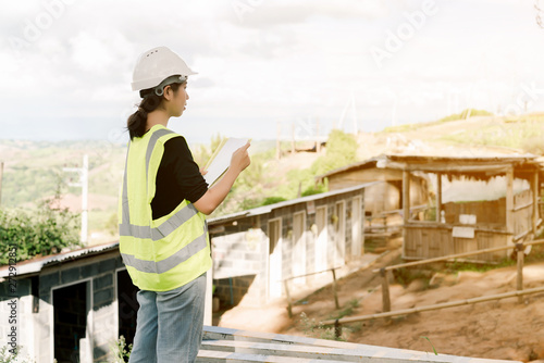 Asian female engineer Put on a white safety hat Wearing a green safety shirt Stand for construction inspection In the construction area