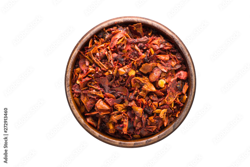 chili pepper flakes spice in wooden bowl, isolated on white background. Seasoning top view