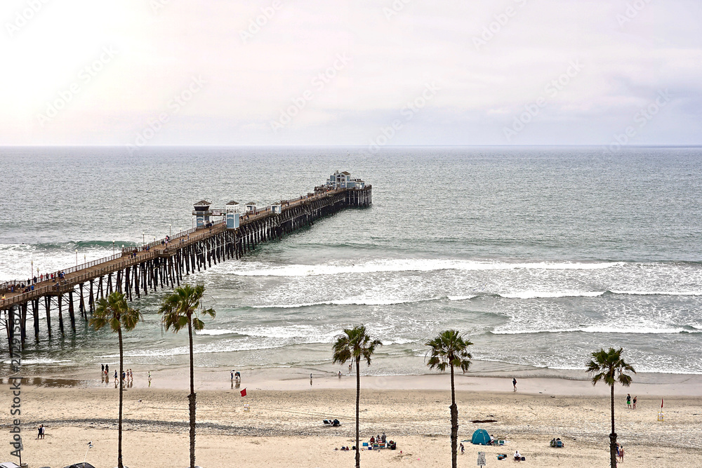 Fototapeta premium OCEANSIDE, CALIFORNIA - 2 JUNE 2019: Oceanside sea view and pier bridge playground and surfboard