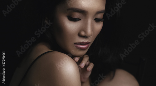 beautiful young woman closeup face and glossy skin under glamour low key concept
