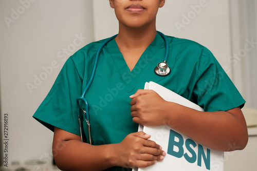 A nurse enrolled in a Bachelor of Science in Nursing degree program, holding a binder in her arms and wearing a stethoscope. photo