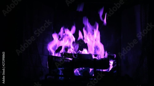 A fireplace flame burns with a magical purple color. photo