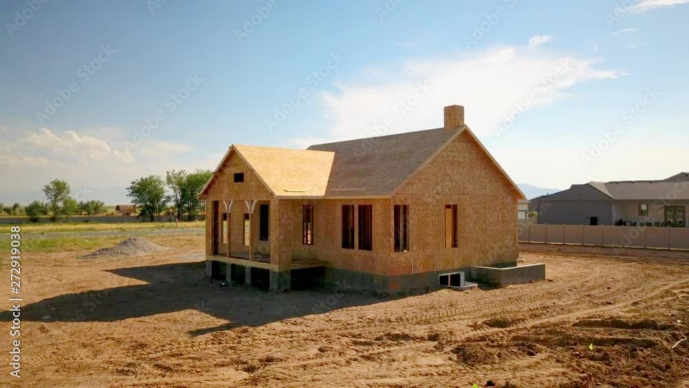 A drone shot pushing in on a recently framed and walled home in the process of a new house getting built. A drone shot pushing in on a recently framed and walled home in the process of a new house getting built.