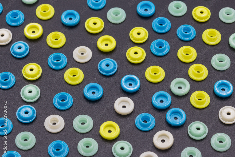 Fototapeta premium Colored round hollow plastic buckles neatly arranged into a beautiful colored grain background