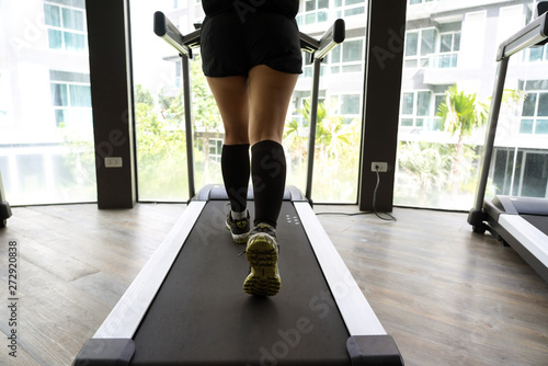 Female legs running on indoor treadmill with bright building background © oppdowngalon