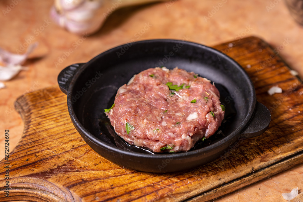 Iron frying pan with raw cutlet on a wooden board Iron frying pan with raw cutlet on a wooden board