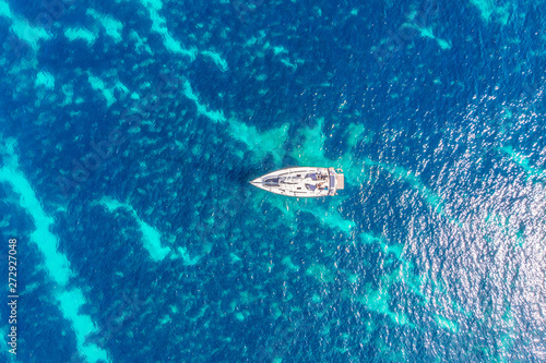 Pleasure white yacht with sail stands on coral reef in blue transparent turquoise water. Concept travel. Aerial top view. © Parilov