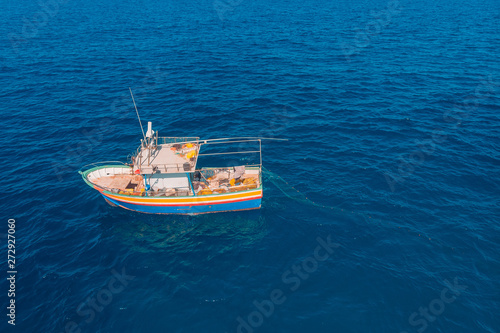 Fishing boat in blue sea water, fishermen set nets for fish. Aerial top view © Parilov
