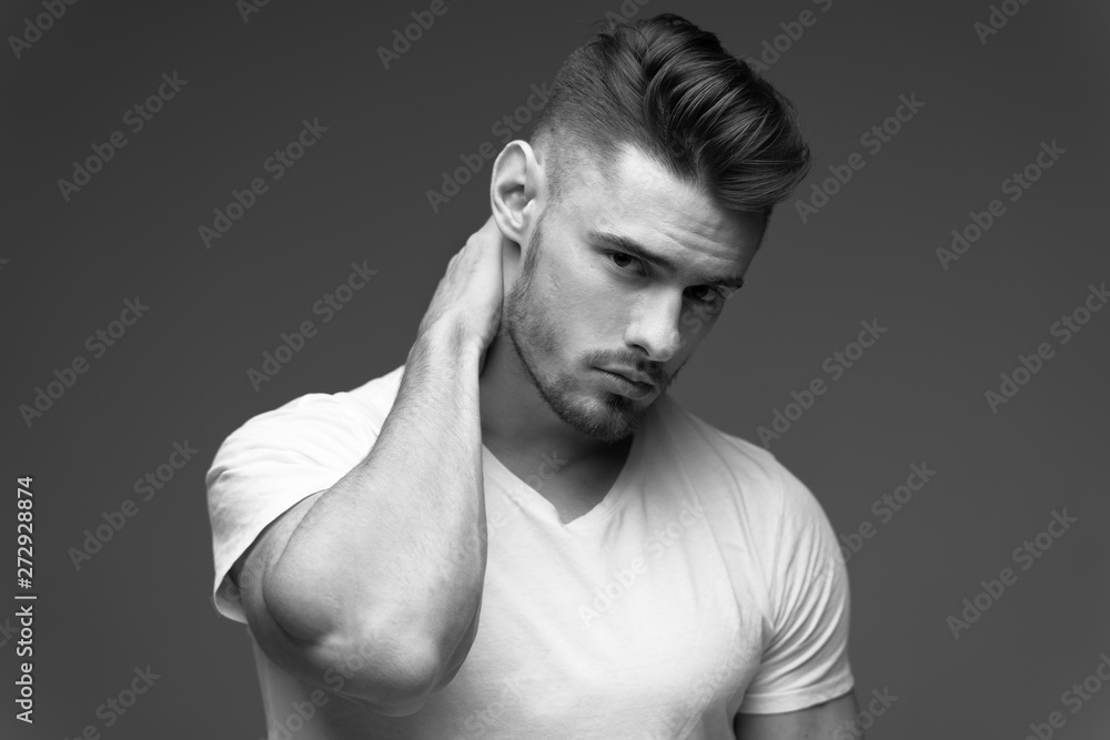 young man with a beard. A man in a t-shirt. Male portrait on a gray background. Stylish man. black and white photo. Sports man. male fitness model. studio portrait