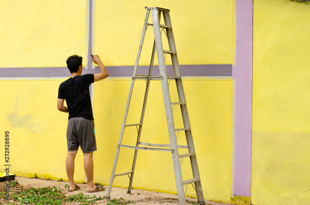 Men are painting yellow color  on the wall.