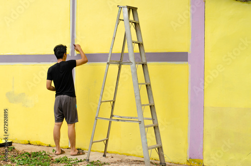 Men are painting yellow color on the wall.