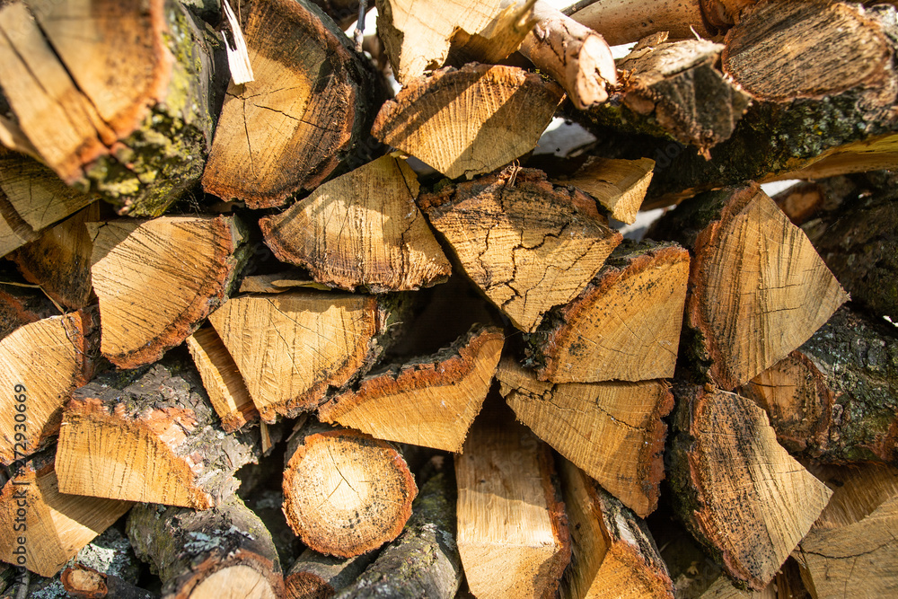 The wall is laid out with the ax by the ax wood in the village, the texture of wooden firewood.