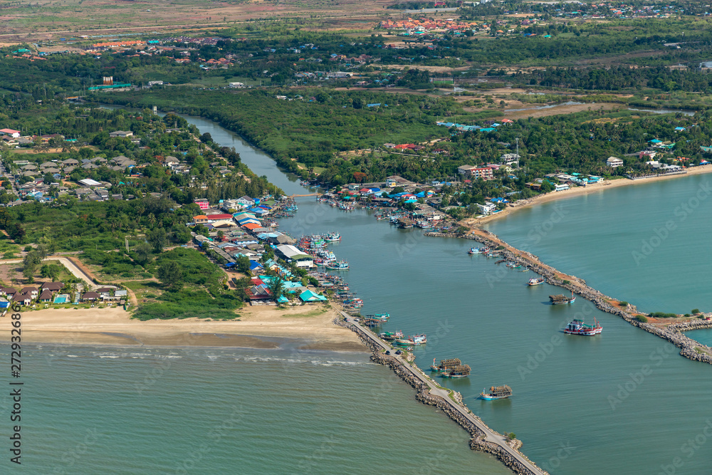 Aerial photo of Cha-am pier in  Phetchaburi Province, Thailand shows many fishing boats parked at the port, preparing to go to catch fish in the blue sea on a sunny day