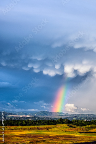 Dramatic storm clouds and a rainbow over the Oroville Dam and the foothills in the background.