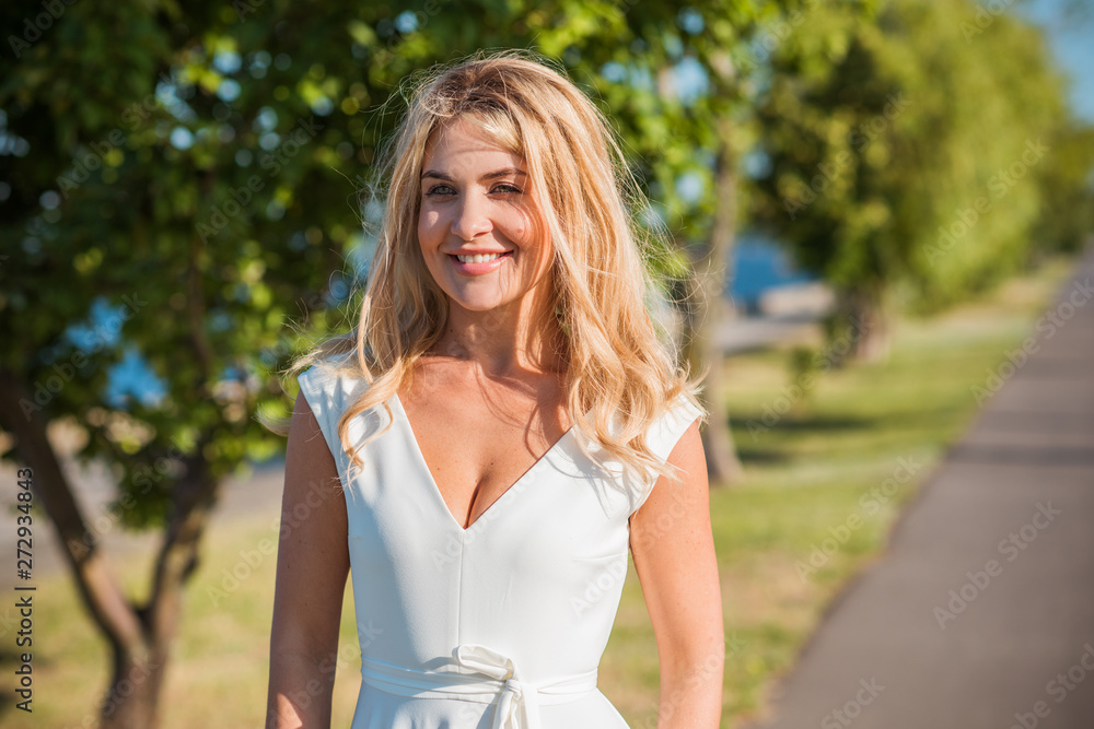 Elegant blonde hair woman in white midi dress at shore. Concept oа white code, fashionable lady, pretty dress and clothes Elegant blonde hair woman in white midi dress at shore. Concept oа white code, fashionable lady, pretty dress and clothes