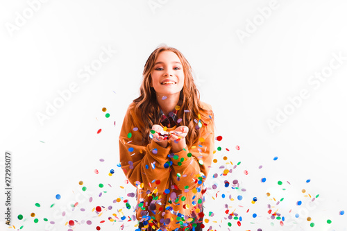 Cute teen girl on a light background throws color candy. Party concept.